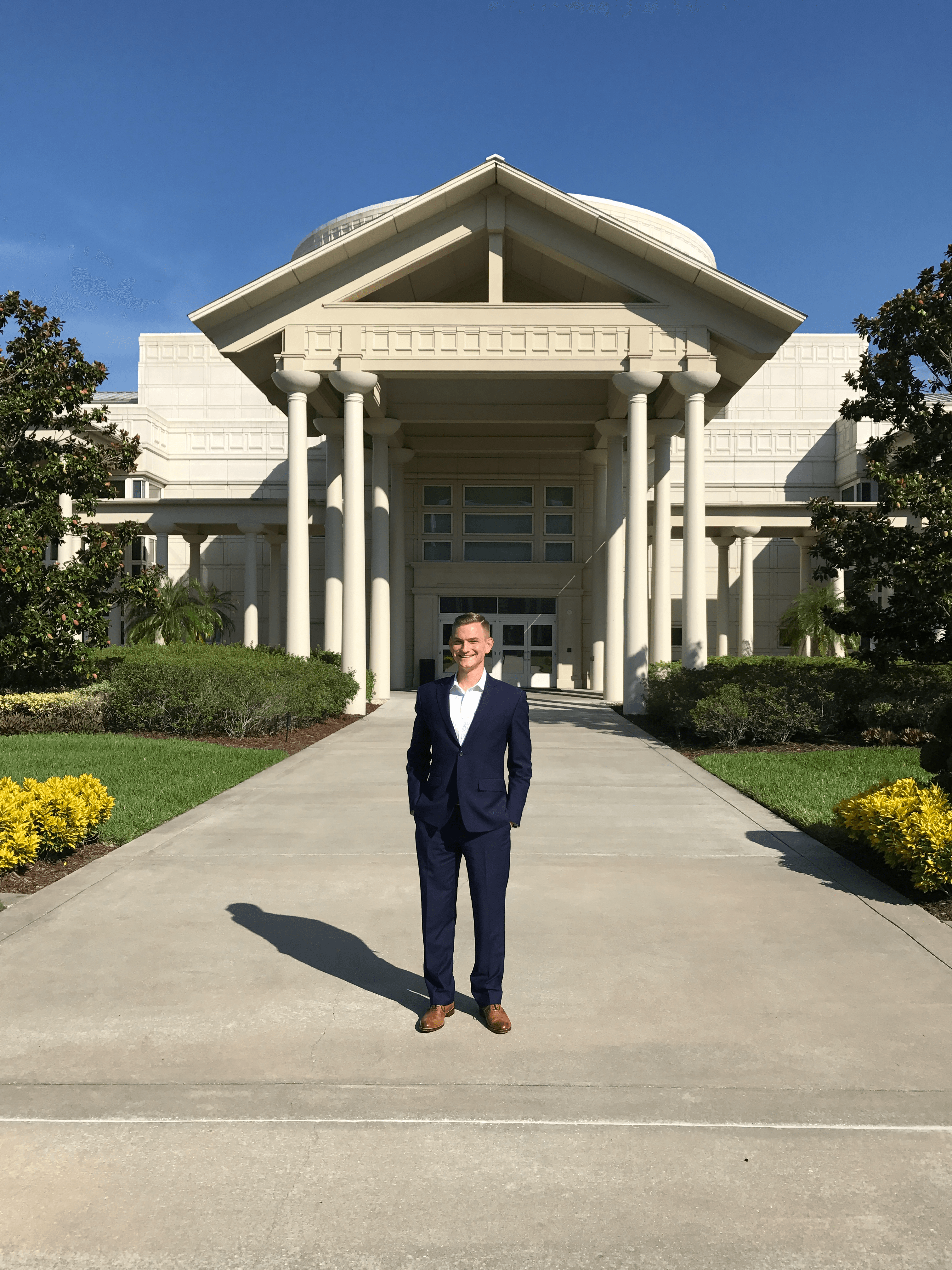 Nate in a suit standing in front of the Orlando Cru global headquarters